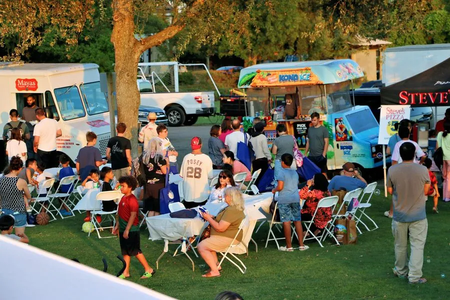 Davis neighbors gathered around food trucks at Family Fun Fest in warm golden evening light