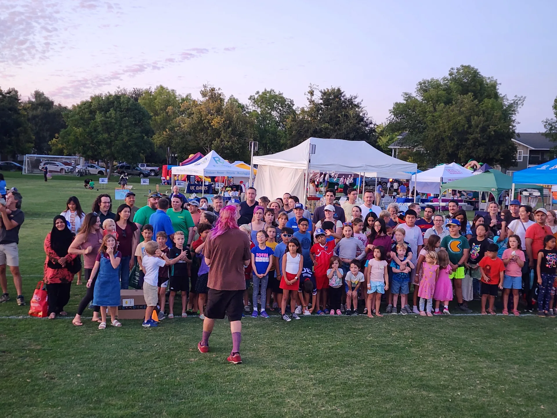 A crowd of Davis families gathered on the field at dusk for Family Fun Fest